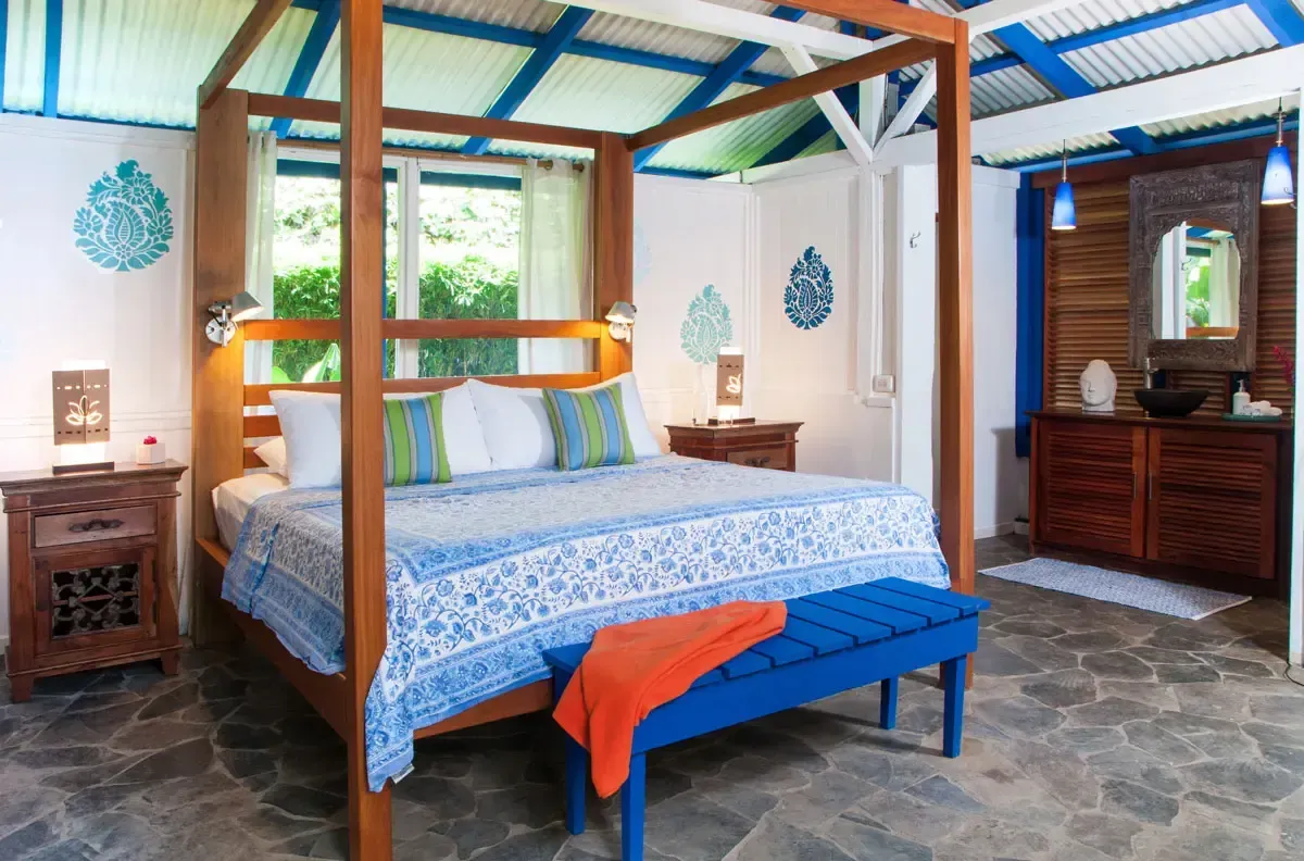A rustic bedroom with wood-paneled walls, a wooden bed frame, patterned bedding, and two bedside lamps.