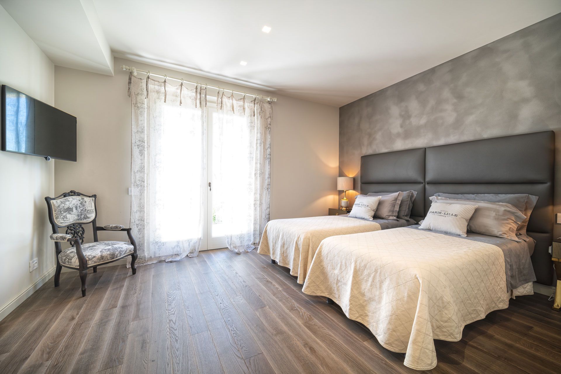 A rustic bedroom with wood-paneled walls, a wooden bed frame, patterned bedding, and two bedside lamps.