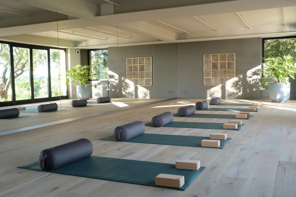A group of people performing yoga on mats inside a large, open-air tent with a projection screen at the front.