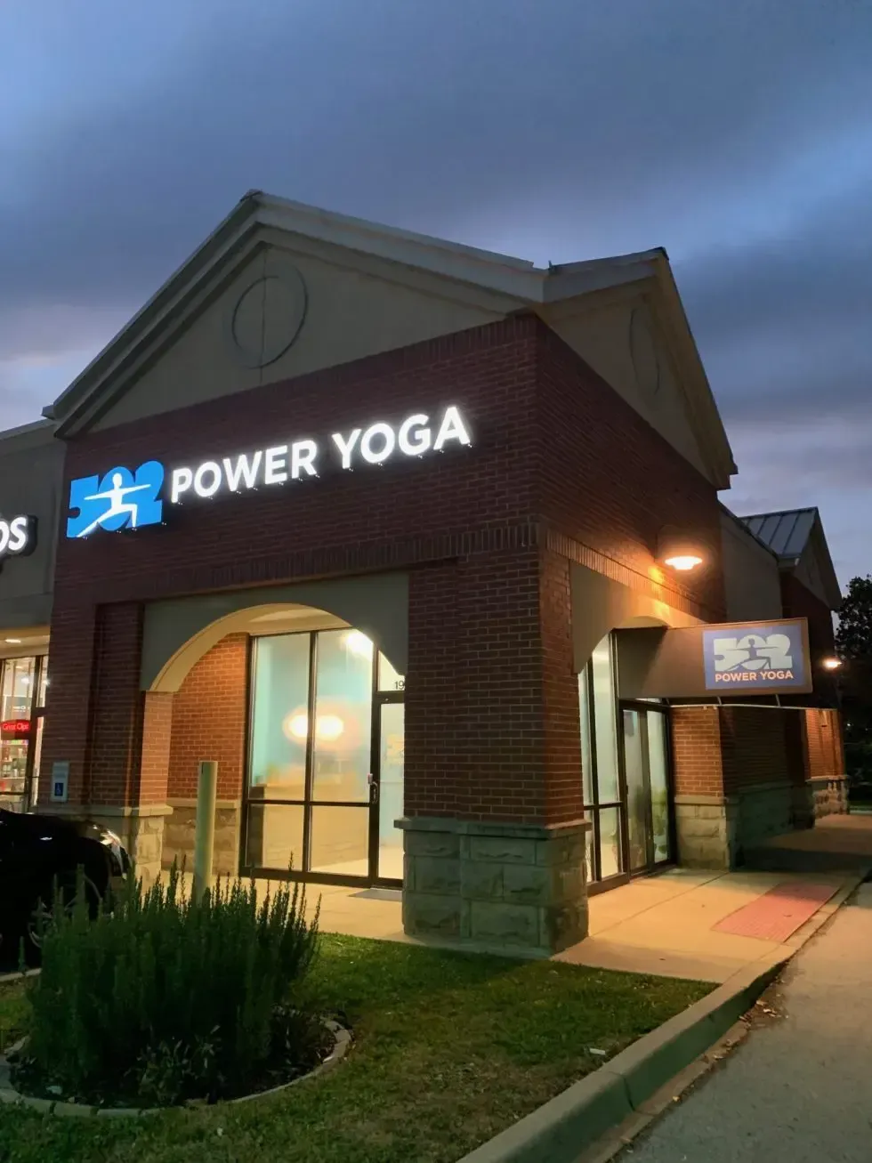 A brick building storefront featuring an illuminated blue and white