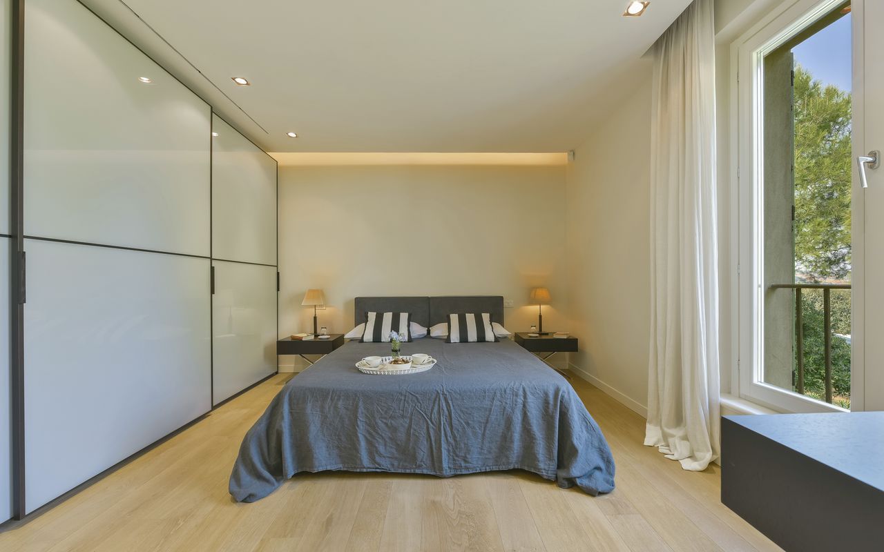 A rustic bedroom with wood-paneled walls, a wooden bed frame, patterned bedding, and two bedside lamps.