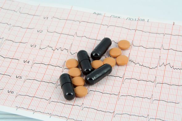 Pillole e capsule sparse su un tracciato ECG che mostra una linea del ritmo cardiaco