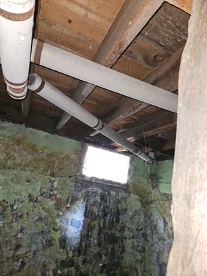 A room with a window and pipes hanging from the ceiling.