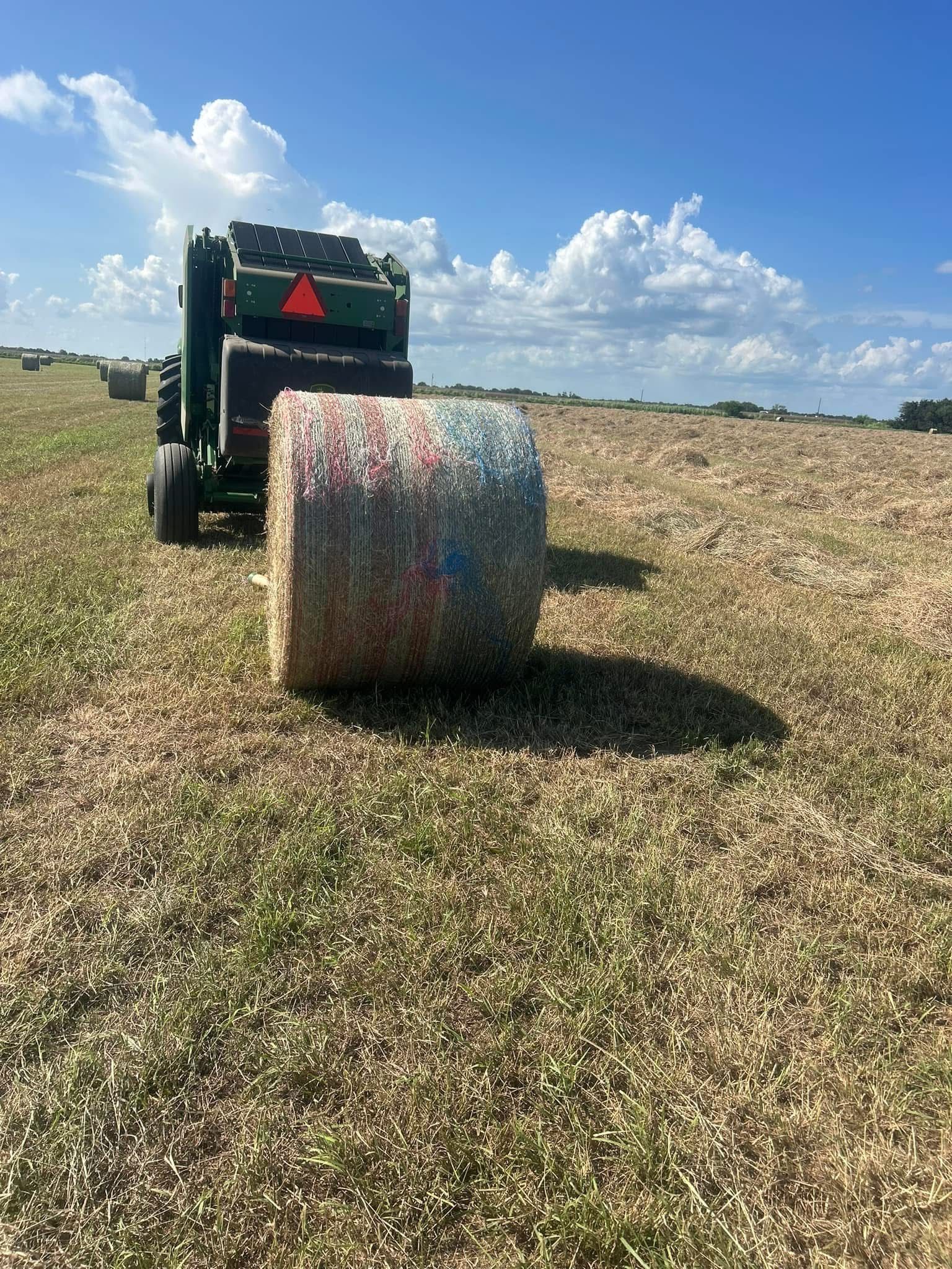 A tractor is baling hay in a field.