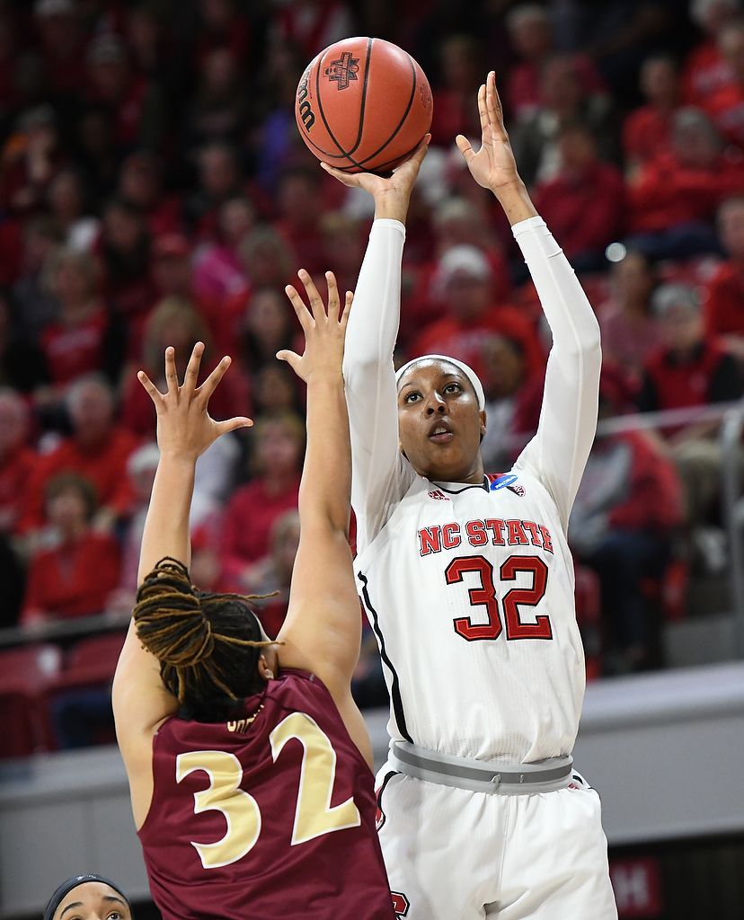 Two basketball players contest a shot, one in white jersey 32 and one in maroon jersey 32, under the hoop