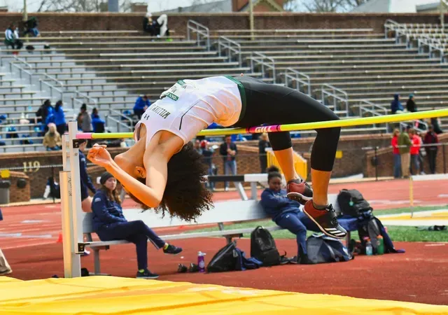 High jumper arches over the bar at outdoor track event.