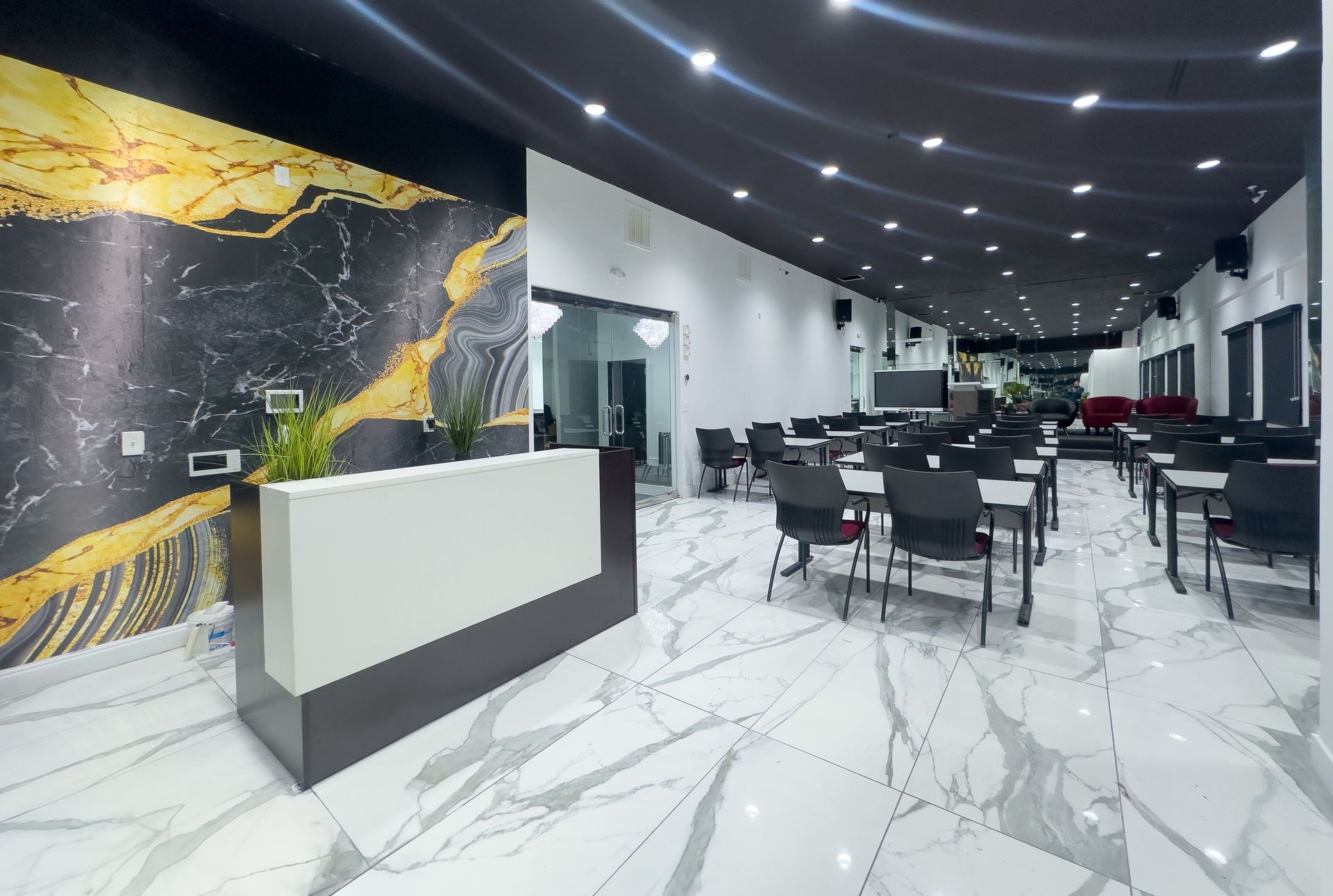 Modern restaurant interior with white marble floors, black tables, and a white reception counter.