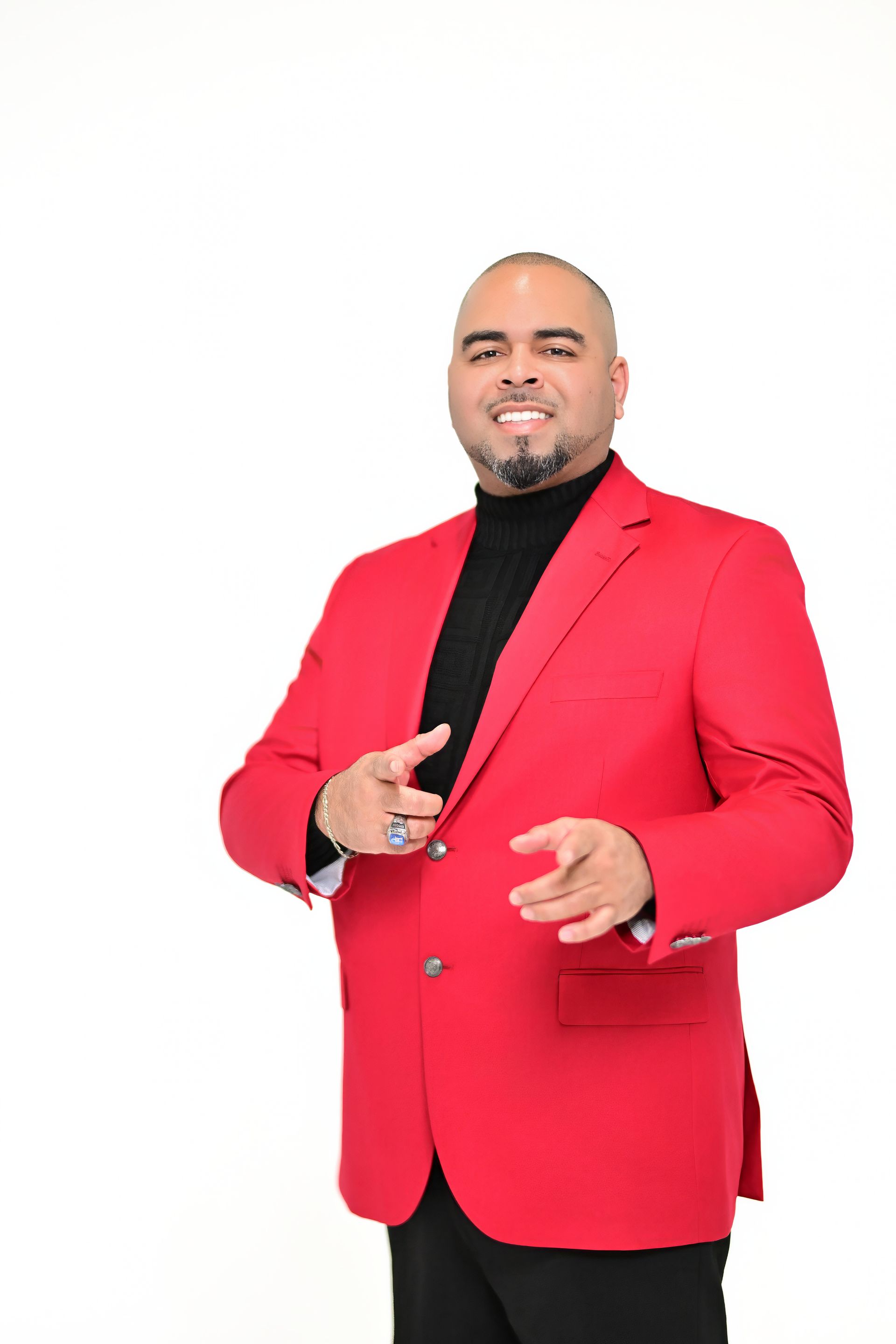 Man in a red blazer over a black turtleneck, posing and pointing against a white background
