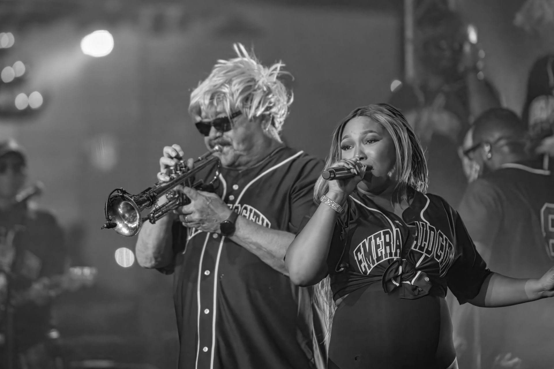 Two musicians performing onstage, one playing trumpet and one singing into a microphone.