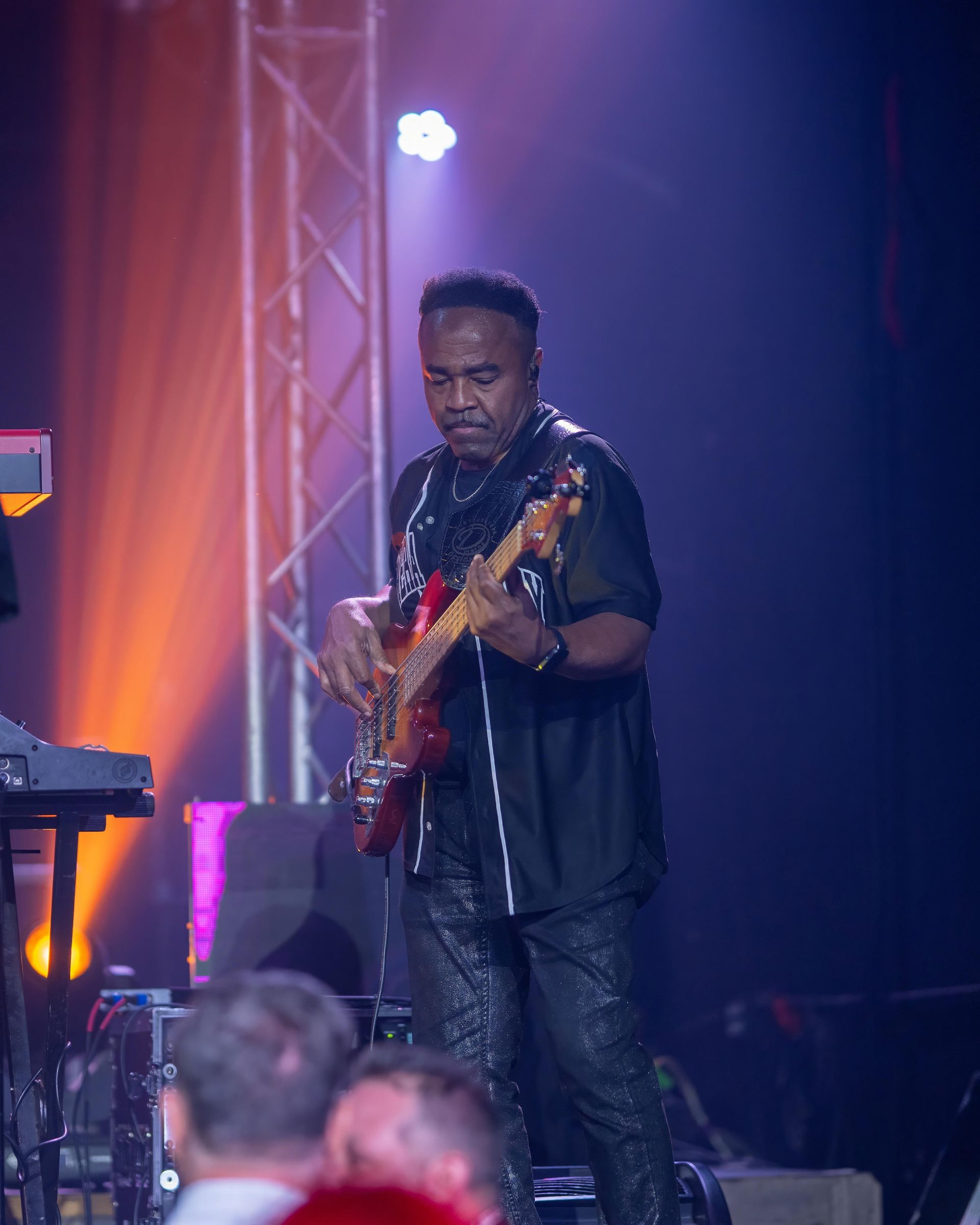 Musician playing electric guitar on a lit stage with purple and orange lights
