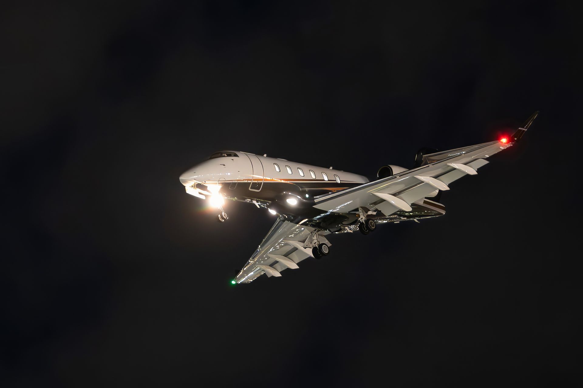 A jet airliner flying at night with landing lights on against a dark sky