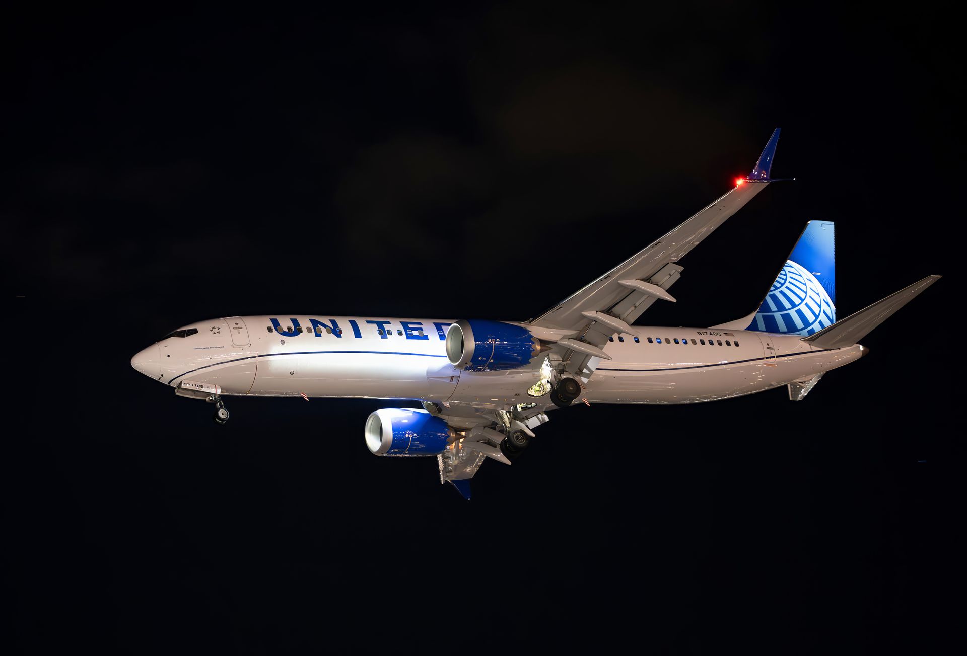 Southwest Airlines plane in flight, blue fuselage, multi-colored wing and tail, descending in a cloudy sky.