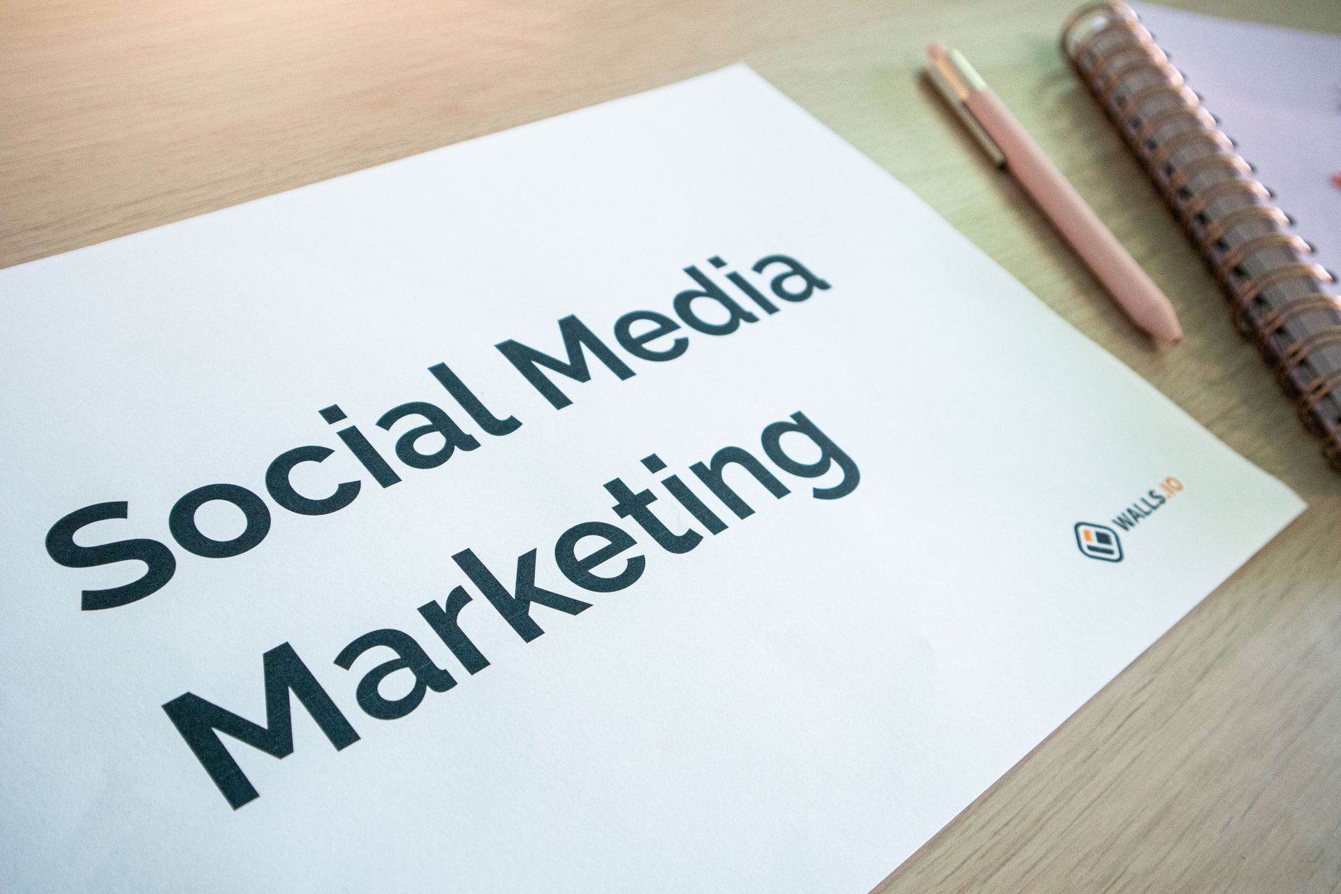 Paper reading “Social Media Marketing” on a desk with pencils and a notebook nearby