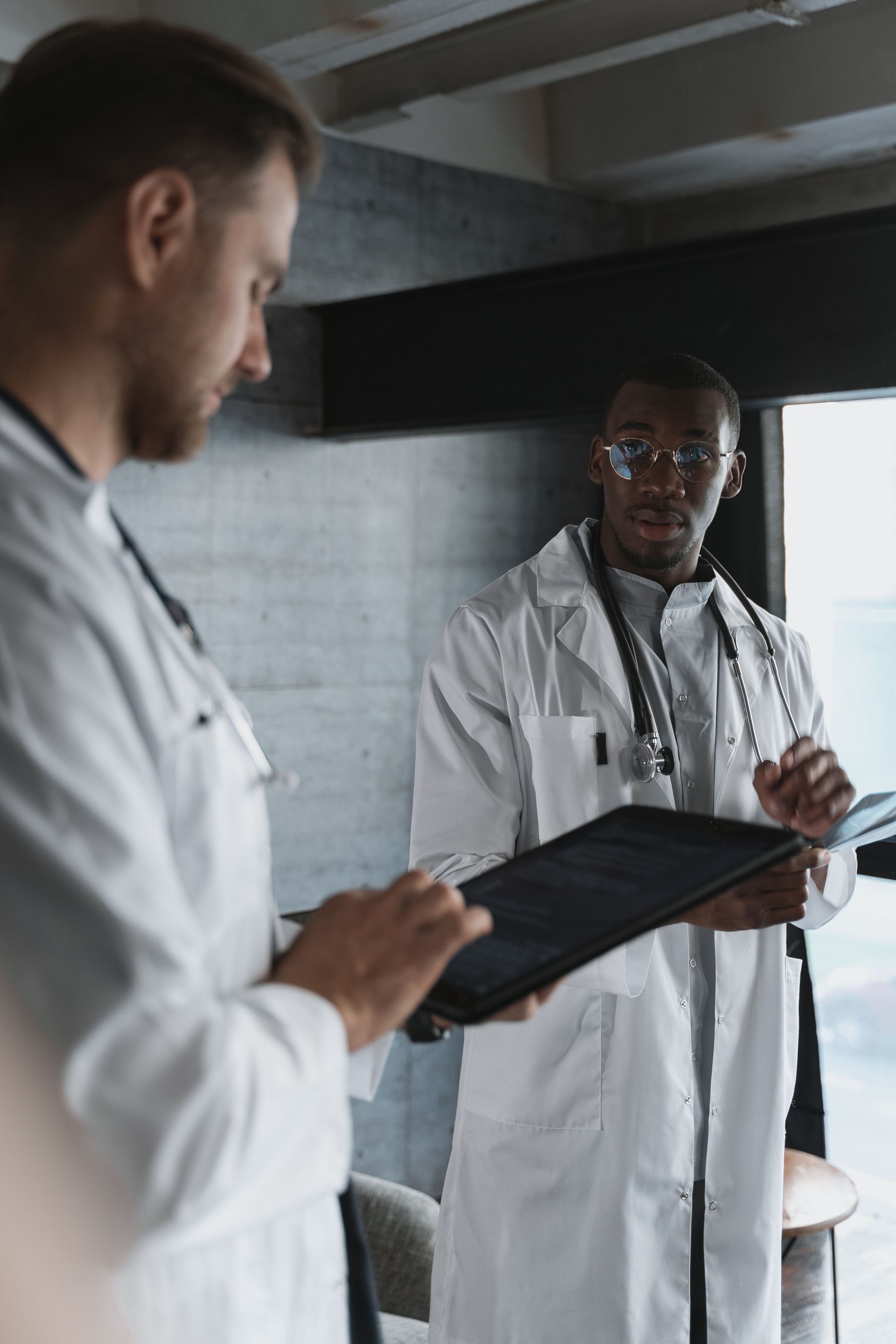 Two doctors in white coats reviewing a tablet in a modern clinic room