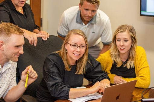 A group of people are looking at a laptop computer.