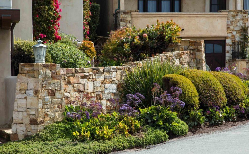 A House With A Stone Wall And A Garden In Front Of It — Mudgeeraba Landscape Centre In Mudgeeraba, QLD 