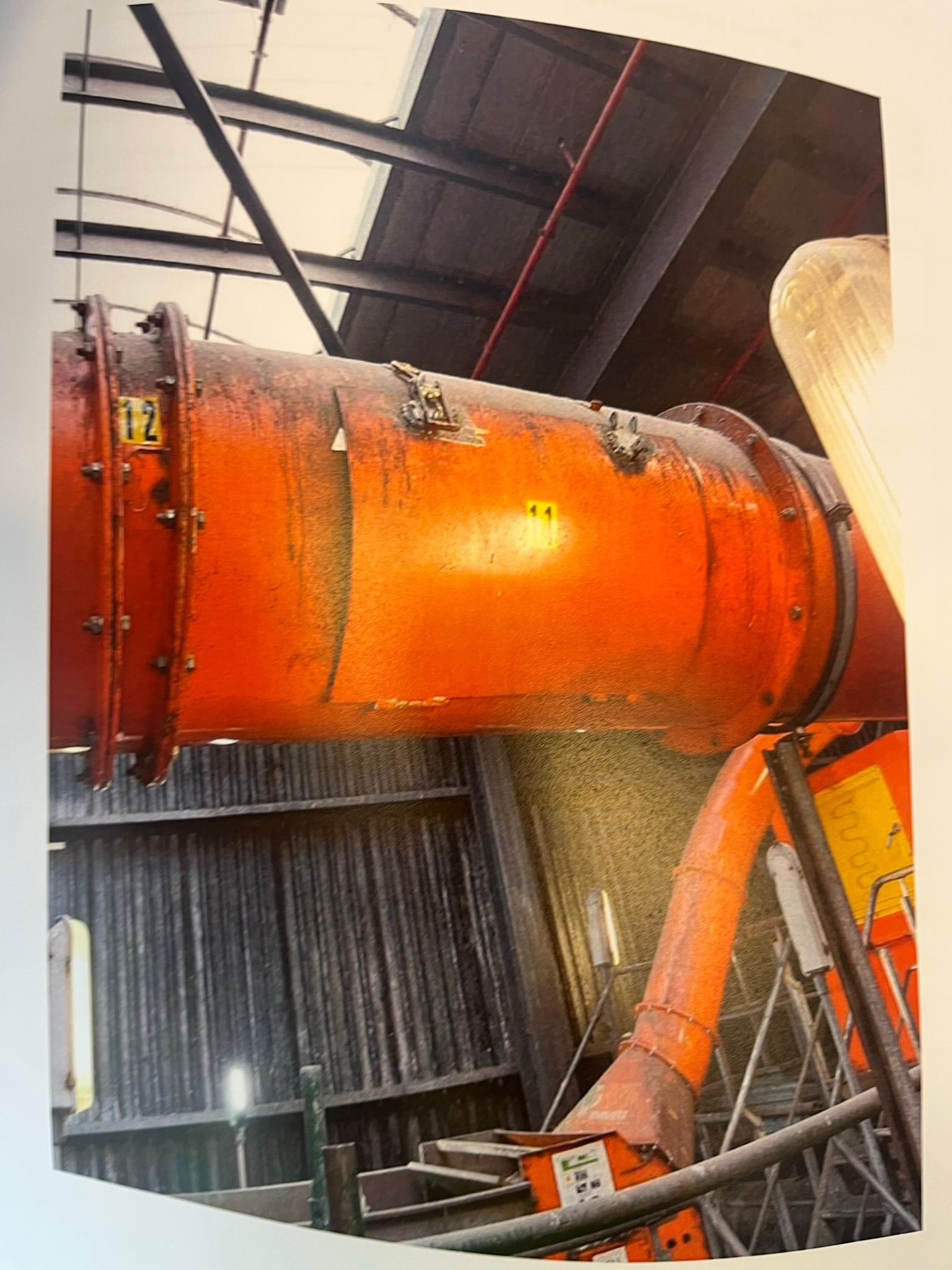 Oranje industriële luchtkanalen in een magazijnomgeving.