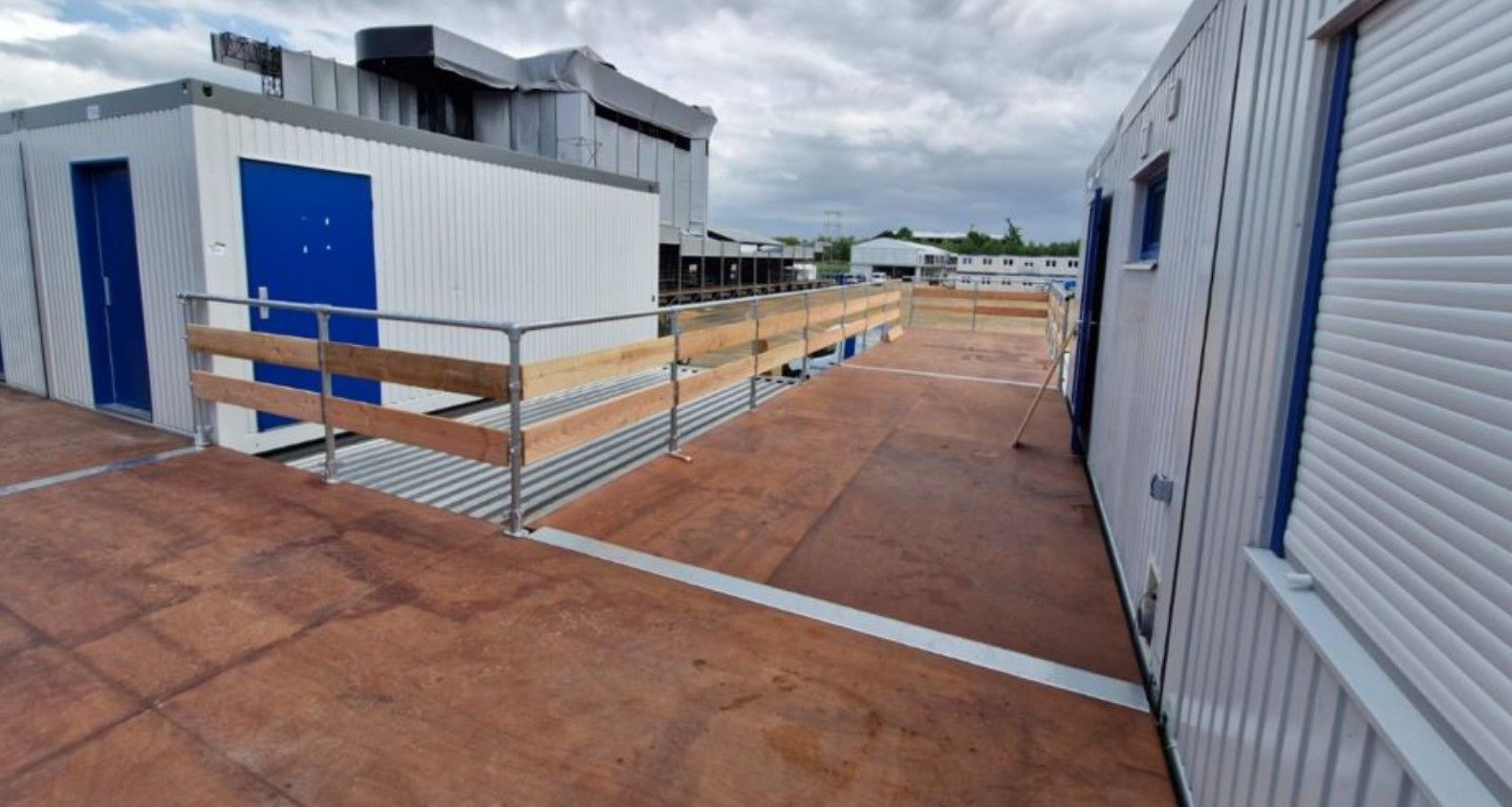 Tijdelijke gebouwen, loopbrug met leuningen, bouwplaats, bewolkt.