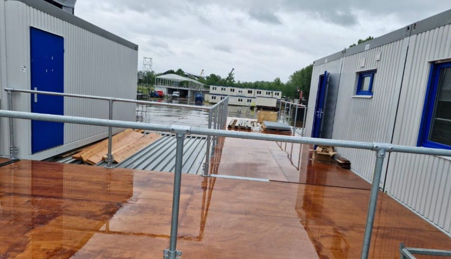 Een rij modulaire gebouwen, verbonden door een hellingbaan met metalen leuningen, onder een bewolkte hemel.