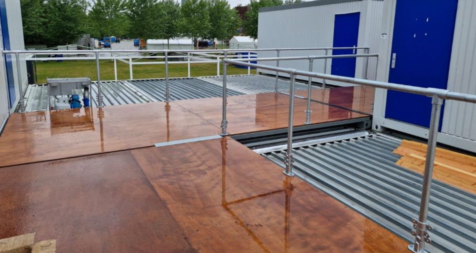 Buitenhelling met leuningen en deuren. Bruine vloer, metalen balken en blauwe deuren.