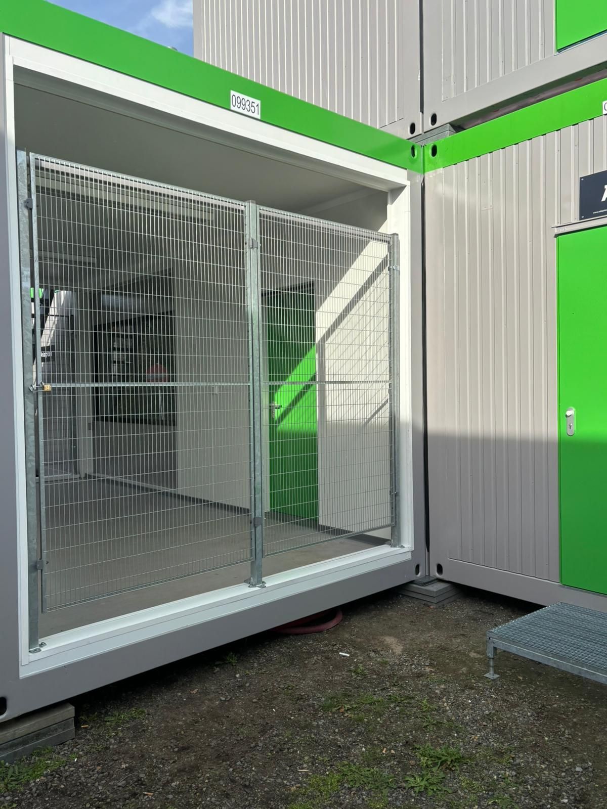 Zeecontainer met open metalen poort en groene accenten.