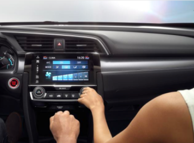 Painel de instrumentos do carro com mãos ajustando os controles de climatização, tela azul.