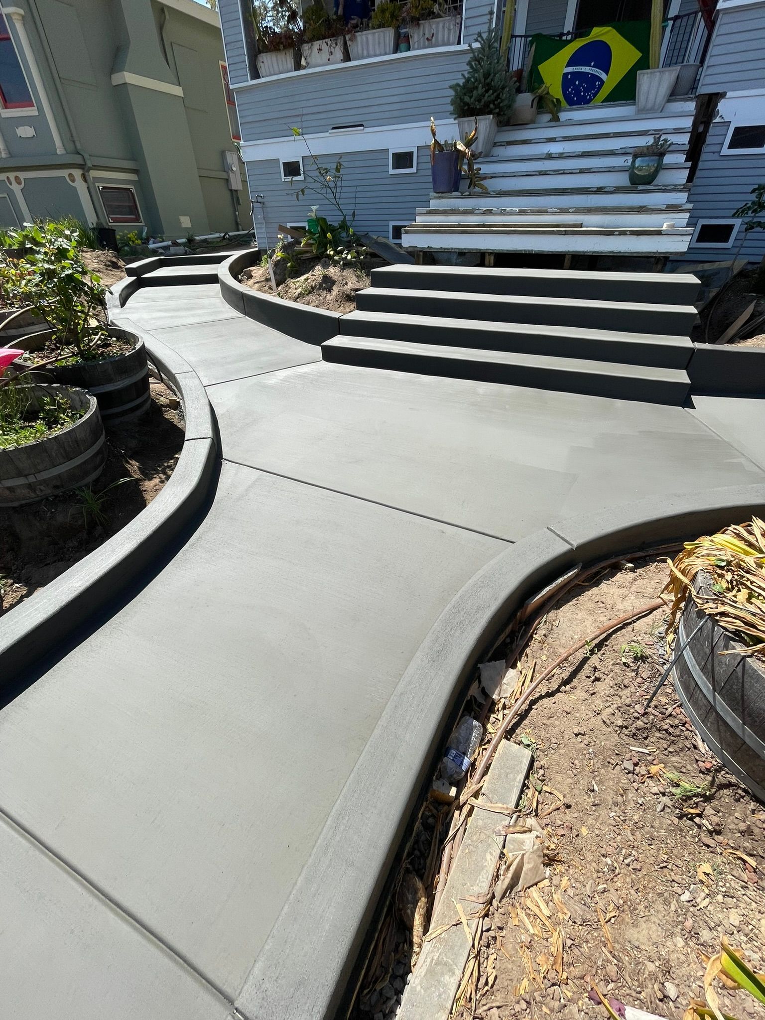 Curved concrete walkway leading to steps and a building entrance with a Brazilian flag in front