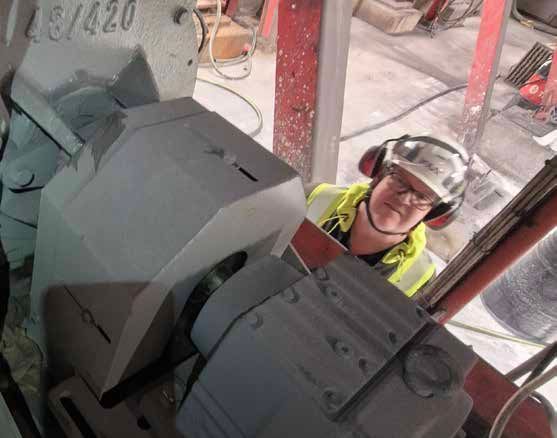 Industriella kanaler och kablar monterade mot en betongvägg bredvid en metallstege.