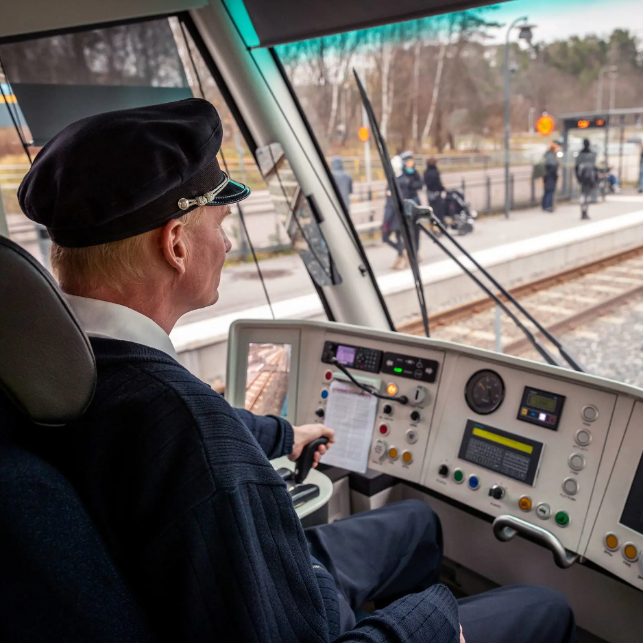 Tågförare vid spakarna på en spårvagn och tittar ut över en snöig stationsperrong.