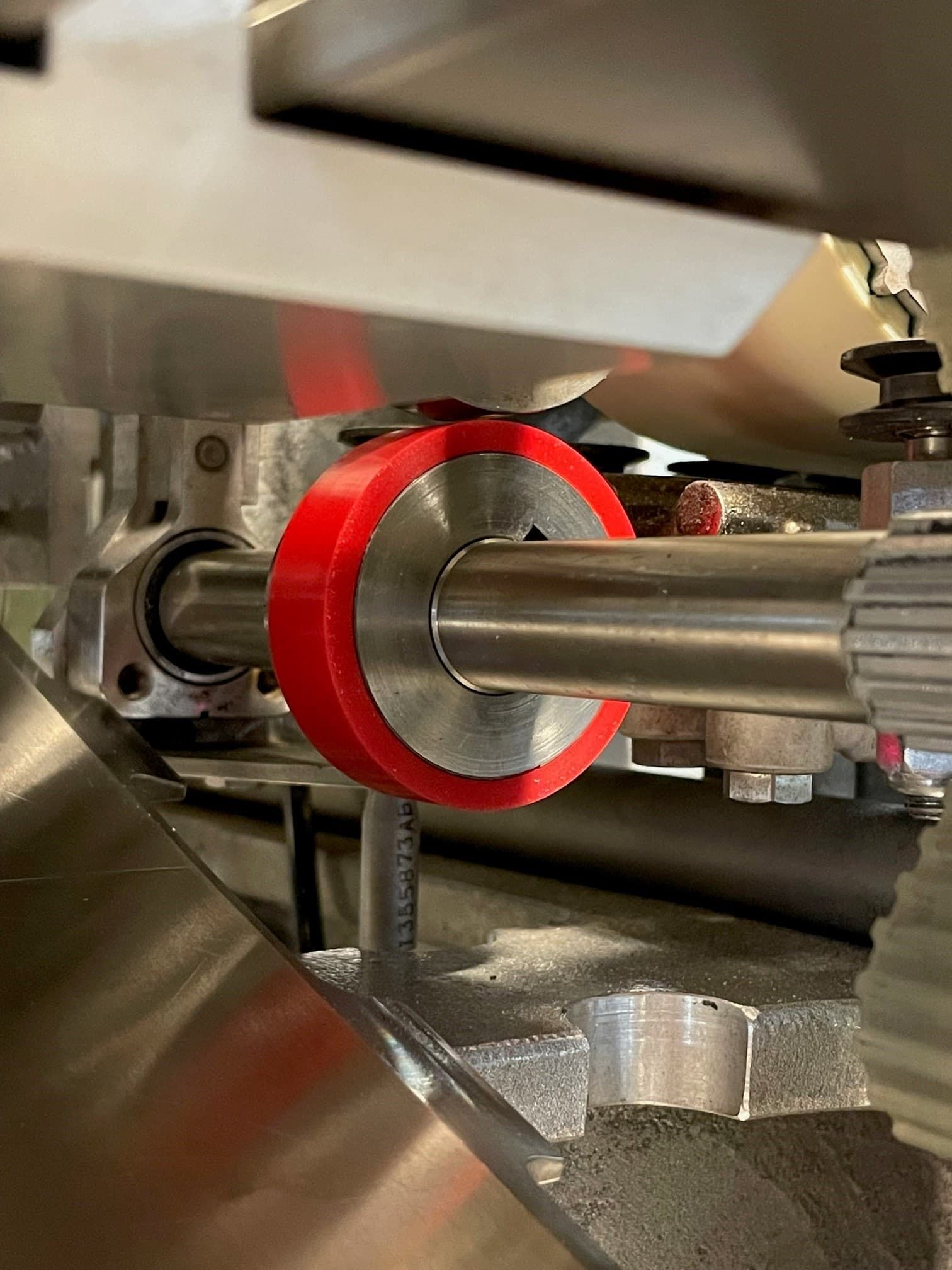 Närbild av ett rött lager runt en metallaxel i industrimaskiner