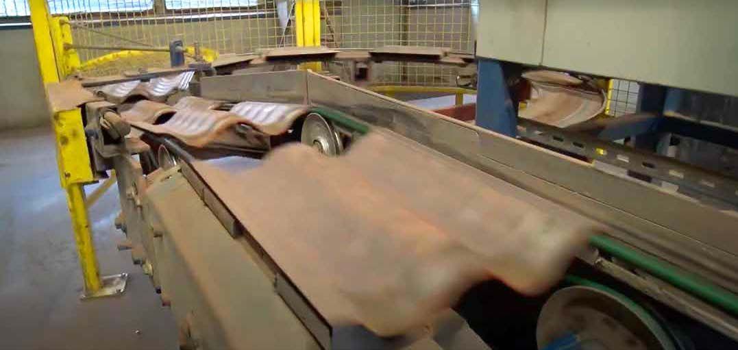 Industriella kanaler och kablar monterade mot en betongvägg bredvid en metallstege.