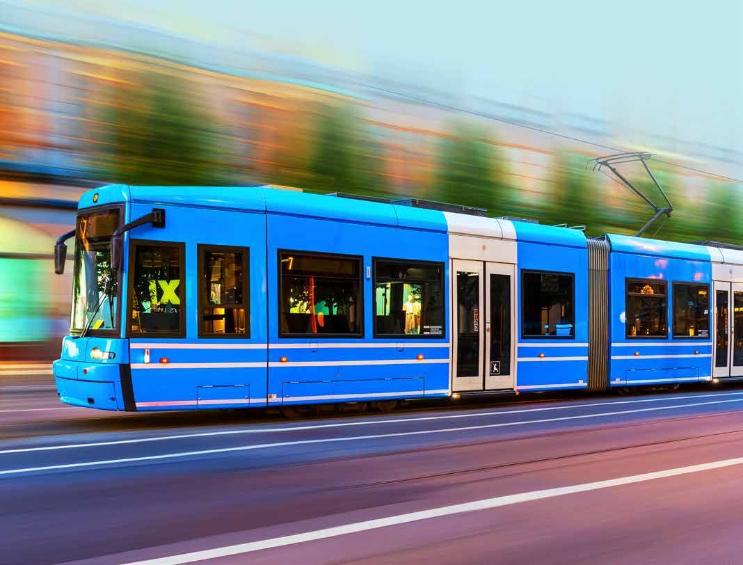 Blå stadsspårvagn som rusar fram längs en gata, med rörelseoskärpa i bakgrunden.