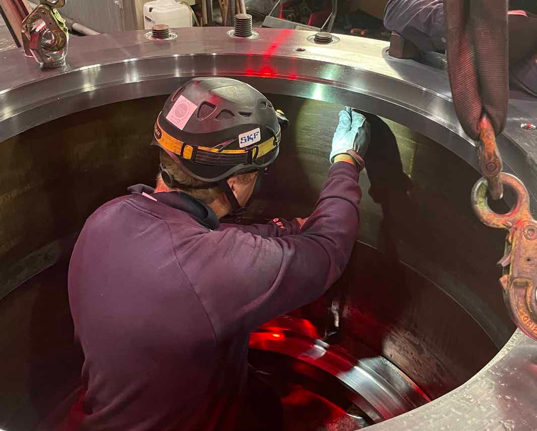 Industriella kanaler och kablar monterade mot en betongvägg bredvid en metallstege.