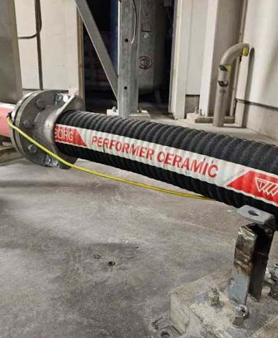 Industriella kanaler och kablar monterade mot en betongvägg bredvid en metallstege.