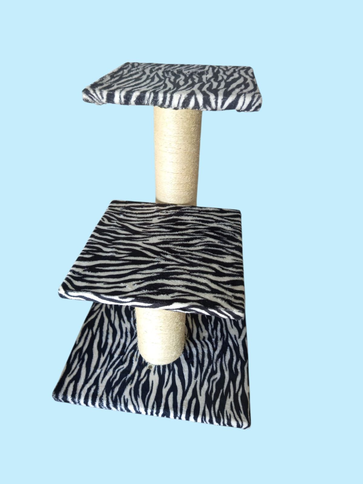 Rascador para gatos con plataformas con estampado de cebra y poste rascador central envuelto en sisal sobre fondo azul claro.