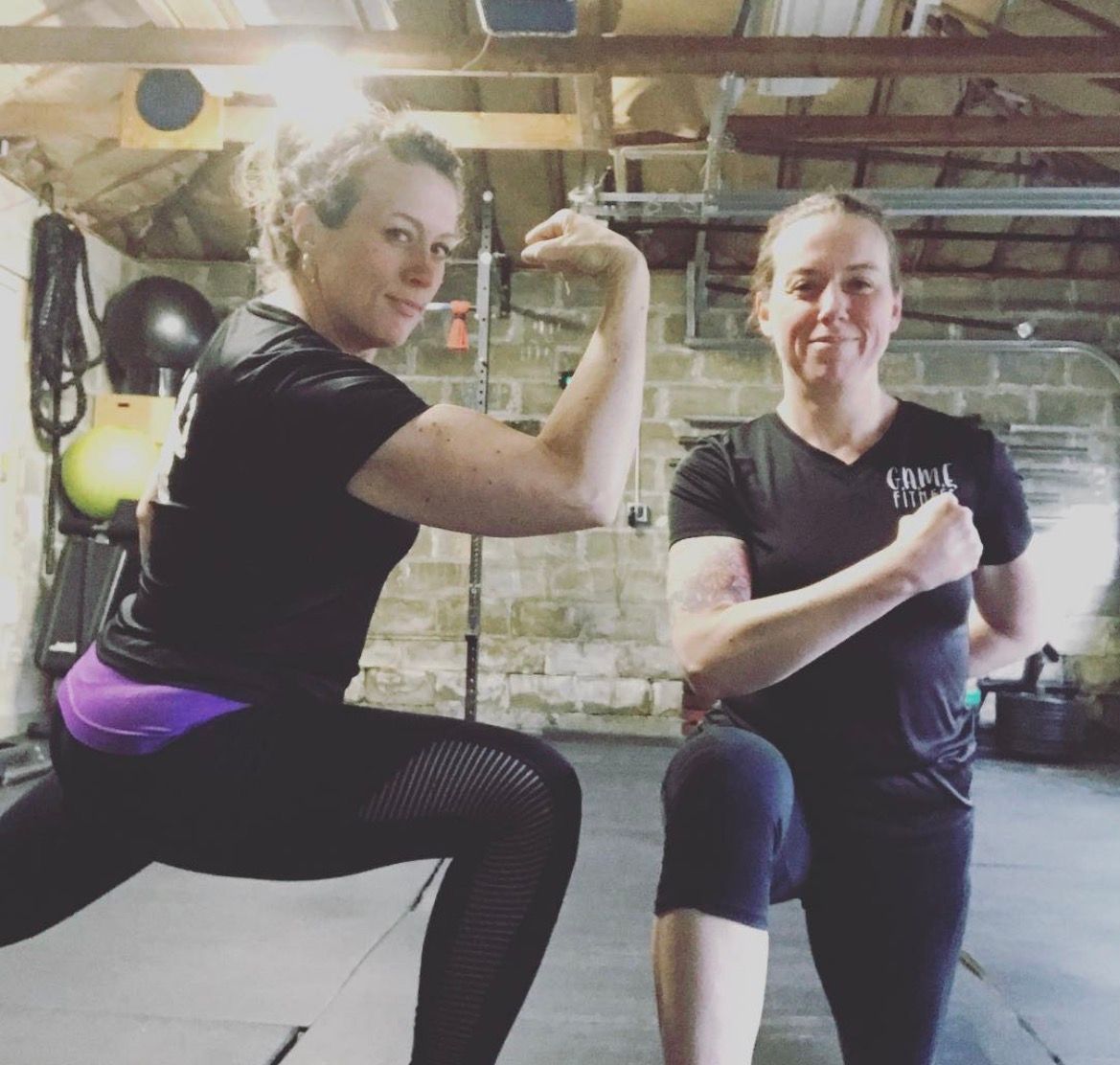 Two people posing in a gym, flexing and lunging in workout clothes.