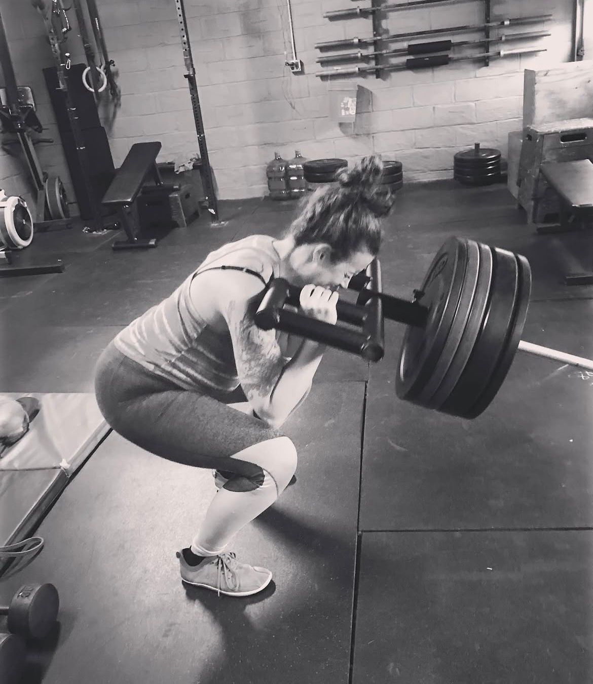 Person back squatting a heavily loaded barbell in a gym.