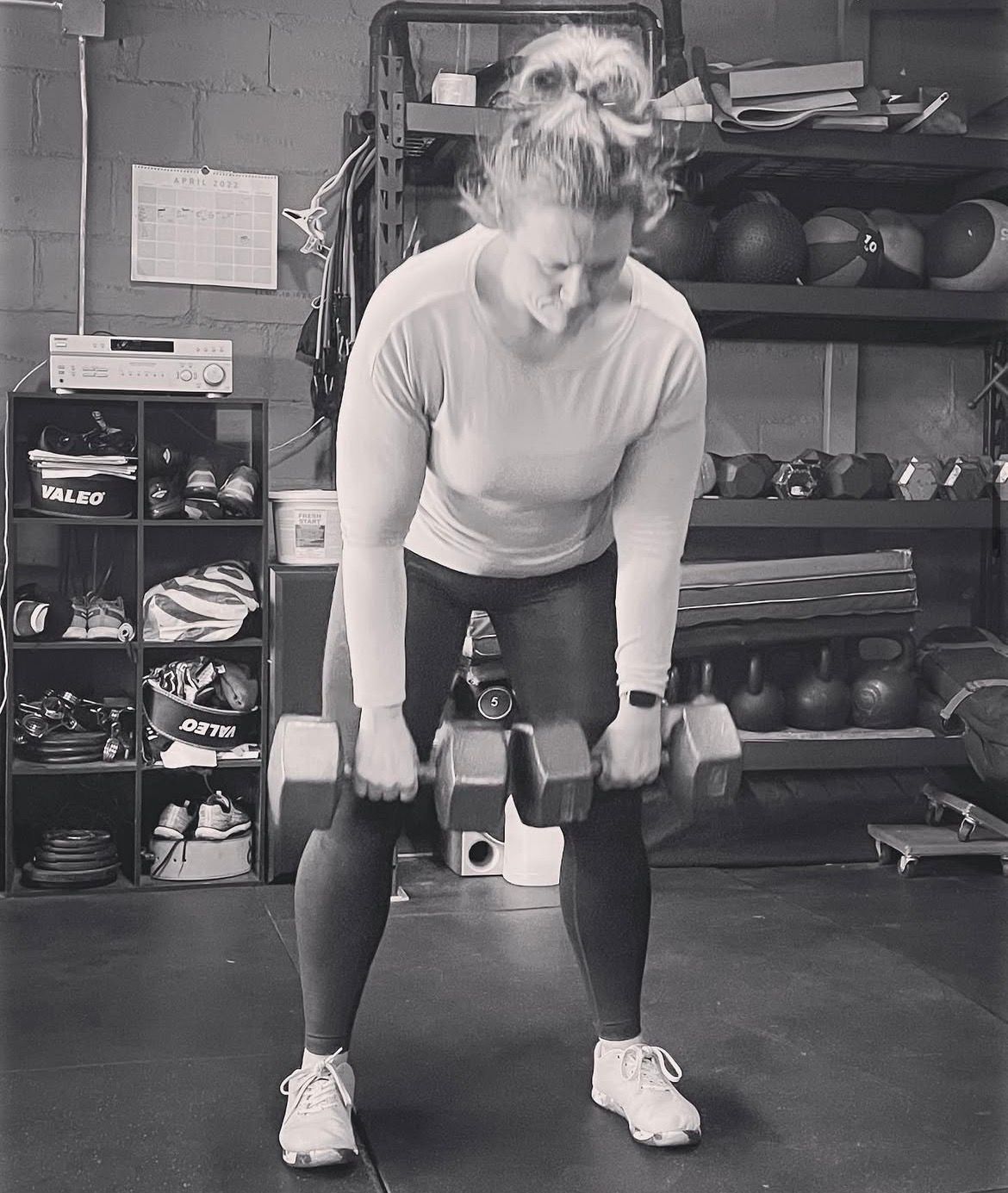 Woman lifting dumbbells in a gym, bent over with a focused posture.