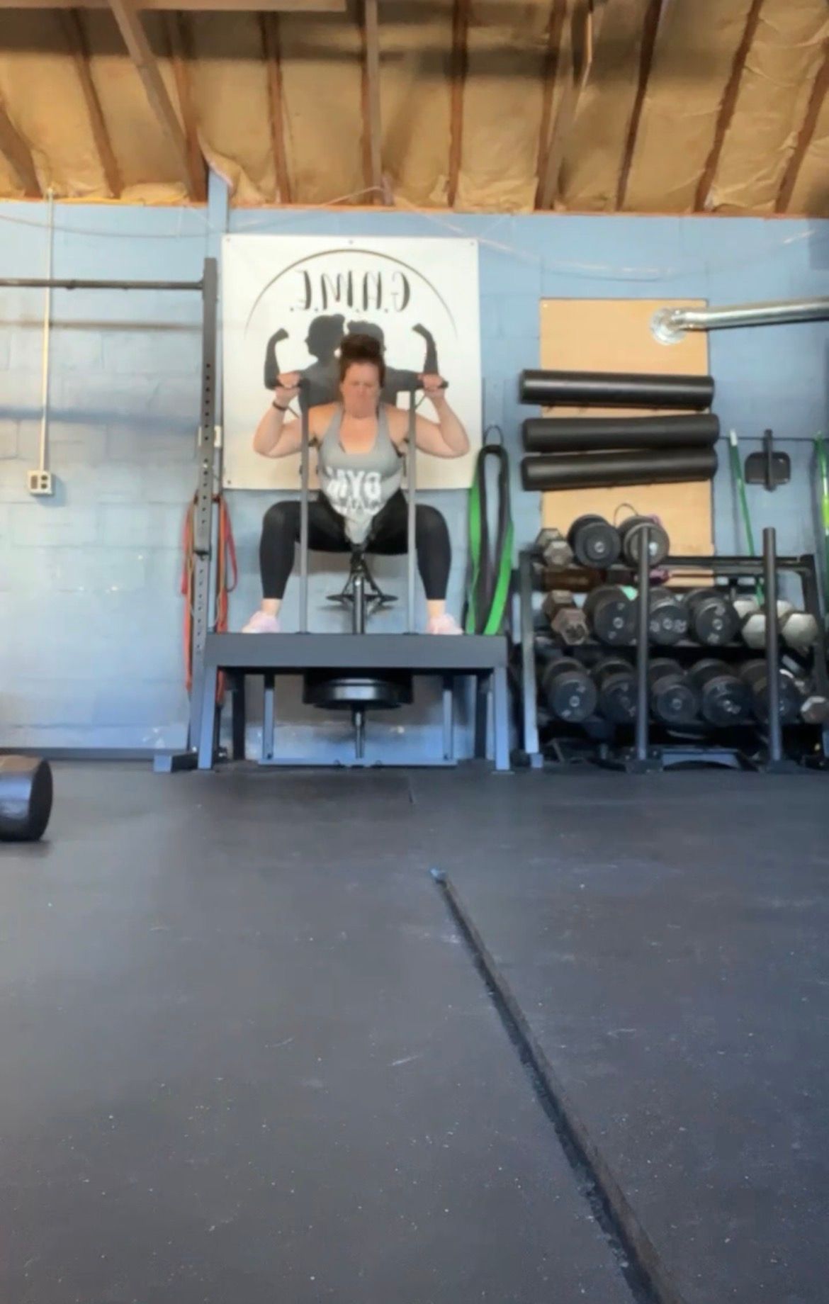 Person lifting weights in a gym with blue walls and racks of dumbbells