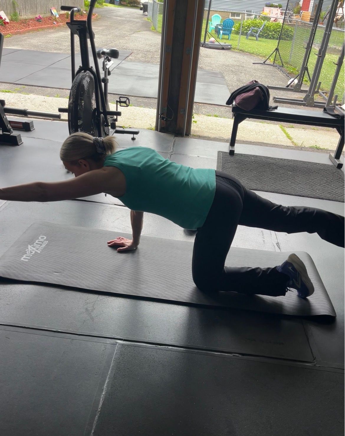 Person doing a floor workout on a mat, extending one arm and opposite leg indoors.