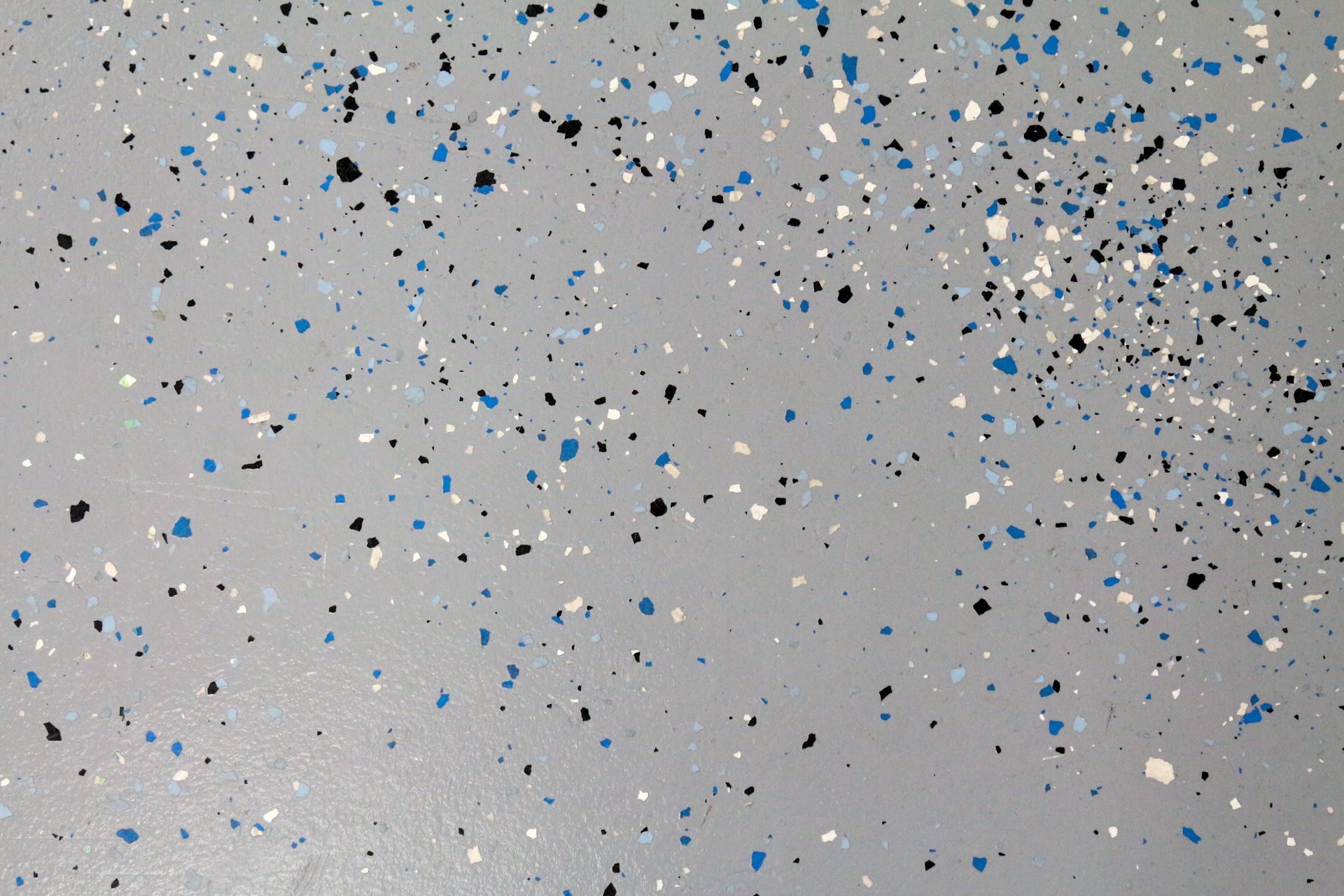 Gray surface with scattered black, white, and blue confetti-like specks