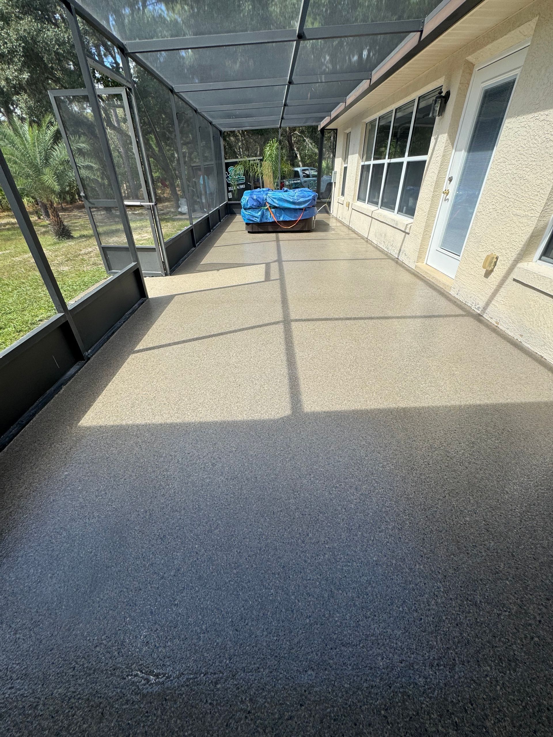 Screened porch with tan floor, white exterior wall, and a blue toy car at the far end