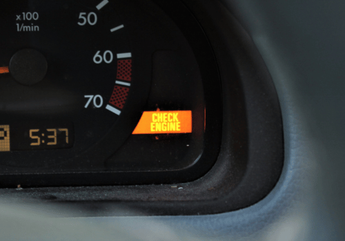 Car dashboard with amber “CHECK ENGINE” warning light illuminated near the speedometer.