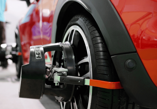 Wheel clamp securing a red car's tire in a parking area
