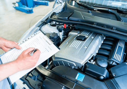 Mechanic inspecting a car engine with a checklist in a repair shop
