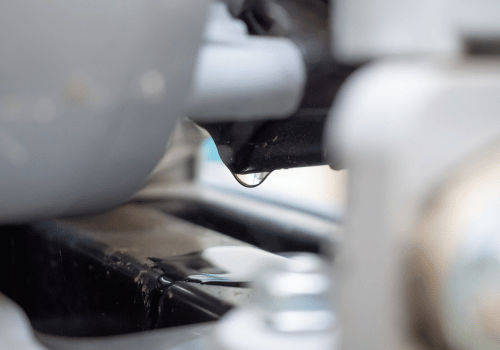 Close-up of a black component with a small water droplet between blurred gray machine parts