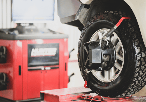 Car wheel being balanced on a red tire machine in an auto repair shop
