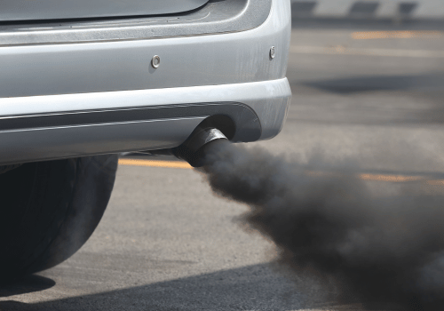 Car’s exhaust pipe releases thick black smoke onto the road.