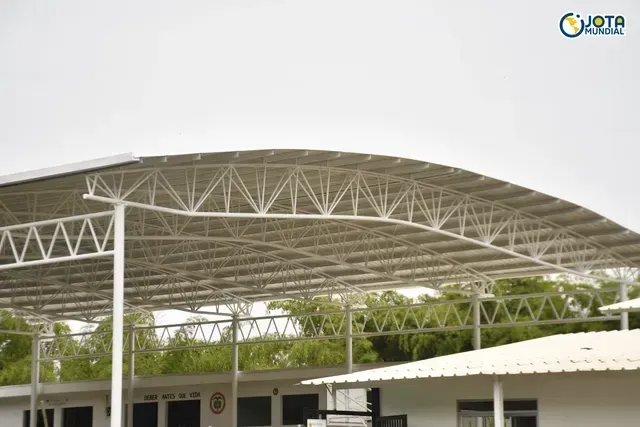 Un edificio blanco con techo de metal y árboles al fondo.