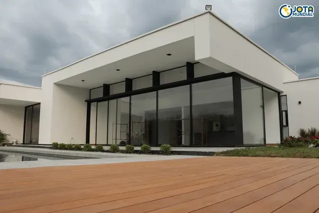 Una casa blanca con muchas ventanas y una terraza de madera en el frente.